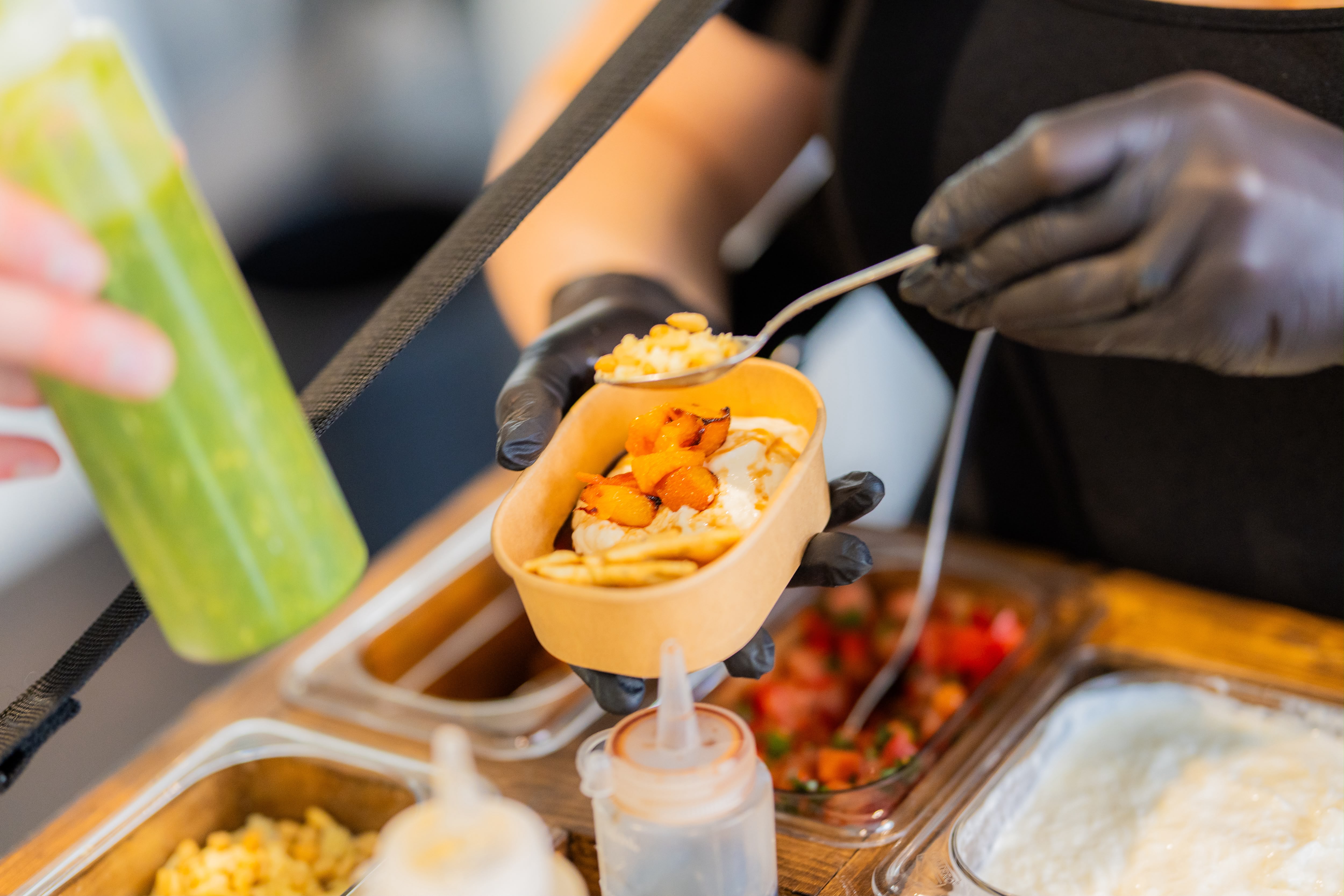 Een burrata-bowl wordt ter plekke opgemaakt boven het hangende dienblad